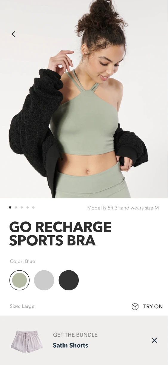 Sports-bra product screen with color choices, size, Try On and a persistent satin-shorts bundle recommendation.